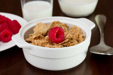 cereals with raspberries in the bowl and glass of milk