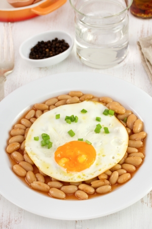 fried egg with beans on the plate and glass of waterの写真素材