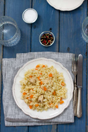 rice with meat and carrot on plate and glass of waterの写真素材