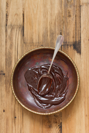 chocolate in dish with spoon on brown backgroundの写真素材