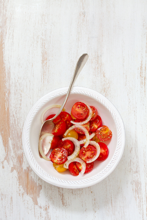 tomato salad in bowl and spoon on white wooden backgroundの写真素材