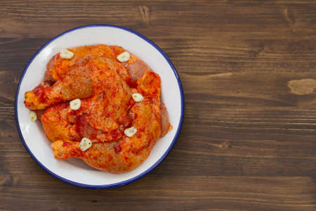 raw chicken with garlic in dish on brown backgroundの写真素材