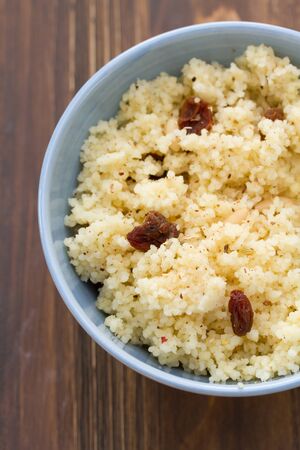 couscous with dry fruits on blue bowl on wooden backgroundの写真素材