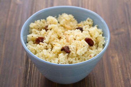couscous with dry fruits on blue bowl on wooden backgroundの写真素材