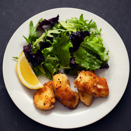 fried squid with salad and lemon on white plate on ceramic dishの写真素材