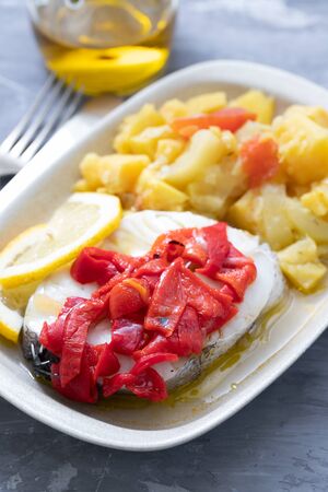 boiled fish with red pepper, vegetables and olive oil on white dishの写真素材