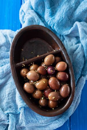 olives in black bowl on blue wooden backgroundの写真素材