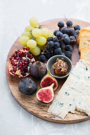 figs with cheese, grapes and honey on wooden boardの写真素材