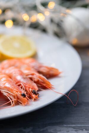 boiled shrimps with lemon and sauce on white dish on ceramic backgroundの写真素材