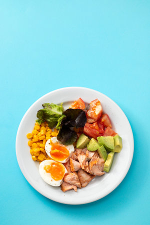 salad salmon with vegetables and boiled egg on white plateの写真素材