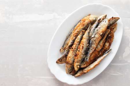 fried small sardines on white dish on ceramic backgroundの写真素材