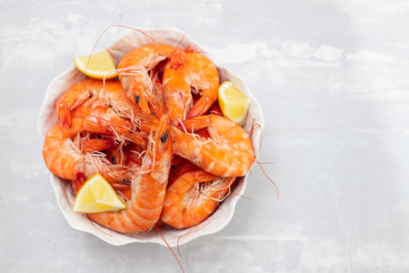 boiled shrimps with fresh lemon in white bowl on ceramic backgroundの写真素材