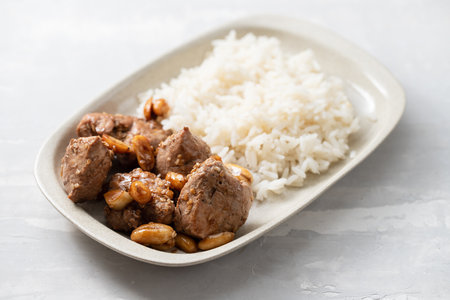 meat with nuts and boiled rice on white plate on ceramic backgroundの写真素材