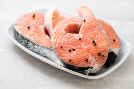 raw salmon with black pepper on white dish on ceramic backgroundの写真素材