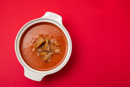 tomato soup in white bowl on red background