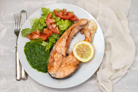 fried salmon with spinach and salad on white plateの写真素材