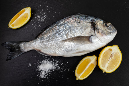 fresh fish wth lemon and salt on black ceramic