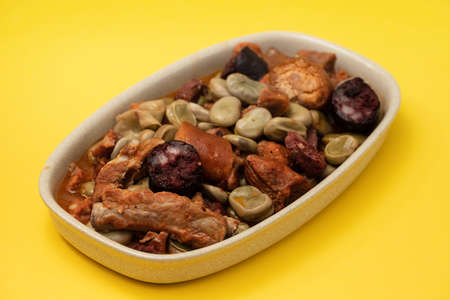 typical portuguese dish beand with meat and smoked sausages on yellow backgroundの写真素材
