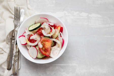 fresh vegetable salad in white bowl on ceramic backgroundの写真素材