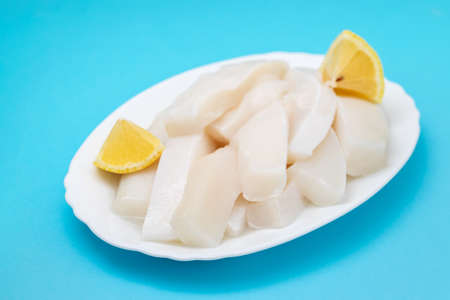raw squid with pepper and fresh lemon on white dish on blue backgroundの写真素材