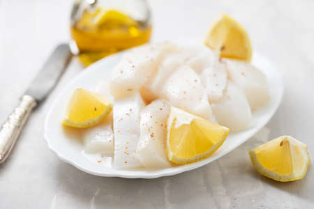 raw squid with pepper and fresh lemon on white dish on ceramic backgroundの写真素材