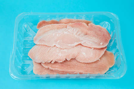 frozen sliced meat turkey in plastic box on blue paper