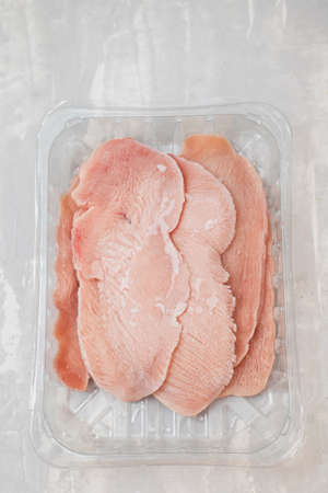 frozen sliced meat turkey in plastic box on ceramicの写真素材