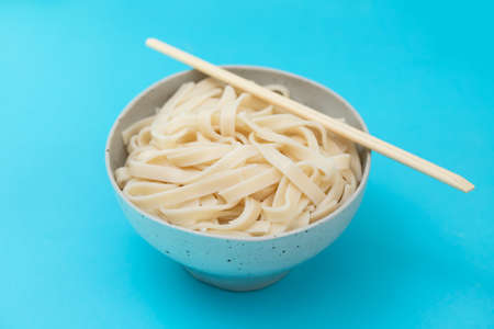 boiled noodle Udon on ceramic bowl on blue paperの写真素材