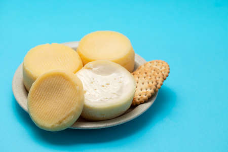 three fresh soft cheese on small dish on blue paperの写真素材