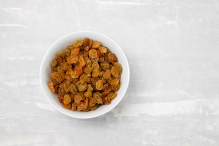 dry yellow grapes in small white bowl on ceramicの写真素材