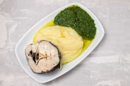 boiled fish with mashed potato and spinach on white dish on ceramicの写真素材