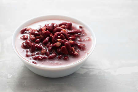 boiled red beans in small white bowl on gray ceramicの写真素材