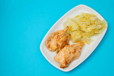 grilled chicken breast with boiled cabbage on the dish on blue paperの写真素材