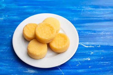 five small cheeses on small white plate on blue woodの写真素材