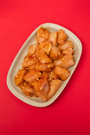 raw meat with marinate on brown dish on red paperの写真素材