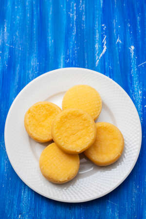 five small cheeses on small white plate on blue woodの写真素材