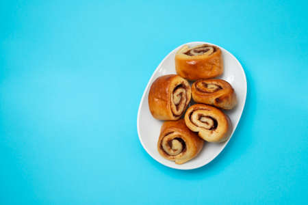 small cinnamon buns on a white dish on blueの写真素材