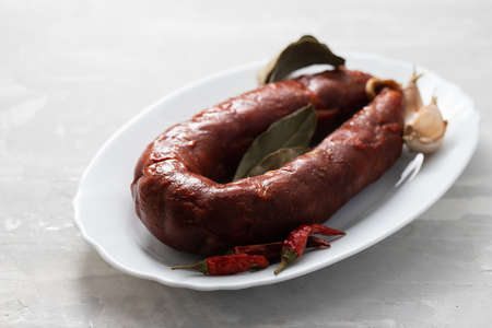typical smoked sausage chourico on white dish on ceramic