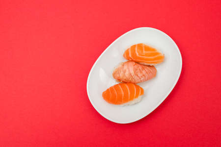 Assorted sushi on small white dish on red paper top viewの写真素材