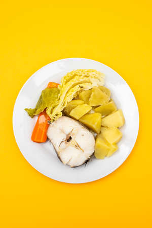 boiled fish with boiled potato, carrot and cabbage on white dish