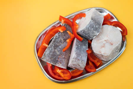 frozen fish with fresh red pepper on dish on yellowの写真素材