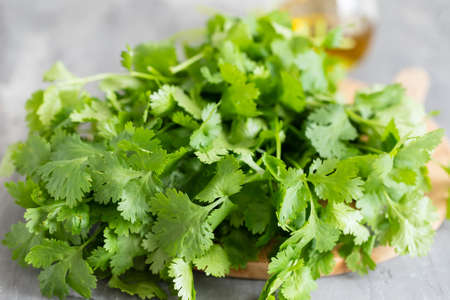 green coriander on wooden board with knife on ceramic