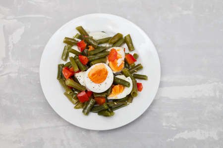 salad green beans, pepper and boiled eggs on white plateの写真素材