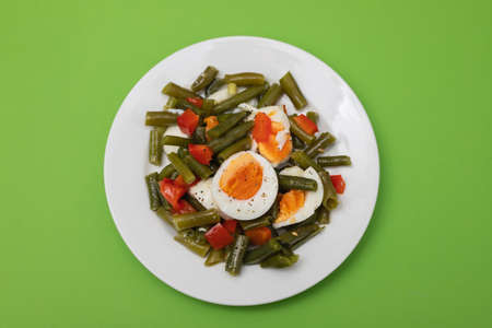 salad green beans, pepper and boiled eggs on white plateの写真素材