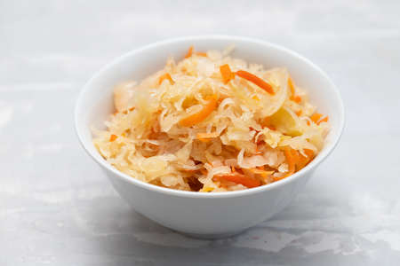 salted cabbage with carrot in white bowl on gray ceramicの写真素材