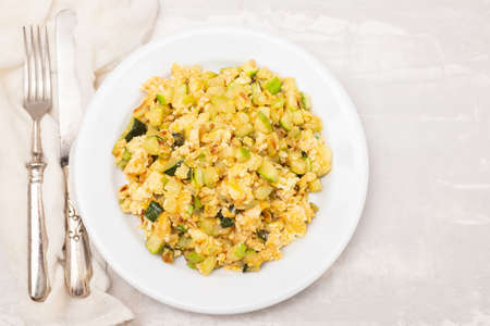 scrambled egg with zucchini on white small plate on ceramic