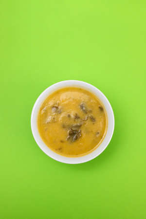 vegetable soup with spinach in beautiful bowl and spoon on green paperの写真素材