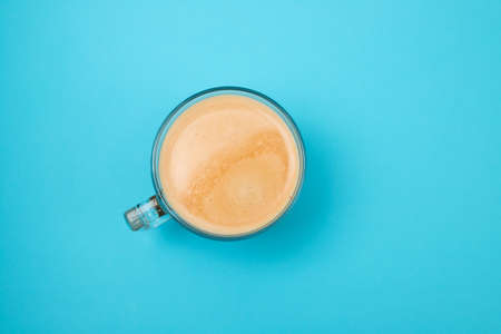 cup of fresh coffee with foam in blue paperの写真素材