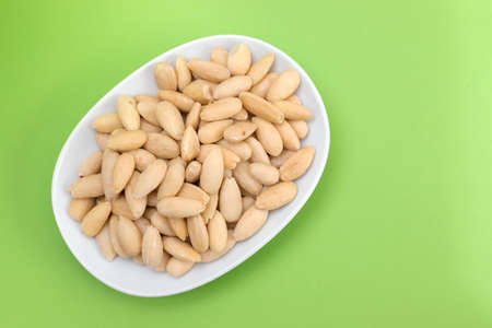 clean almonds on small white dish on greenの写真素材