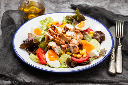 Delicious light vegetable salad made from tomatoes, canned corn, cucumber, lettuce, avocado, boiled egg andchickenの写真素材